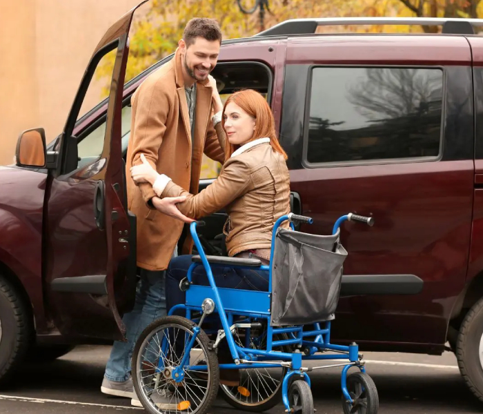 Man helping a woman into a car, using NDIS Transport Support